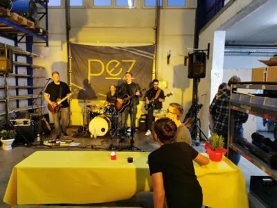 Live-Band spielt in der Werkhalle, Gäste an gedeckten Tischen